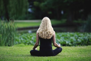A woman with blonde hair sat in a park meditating