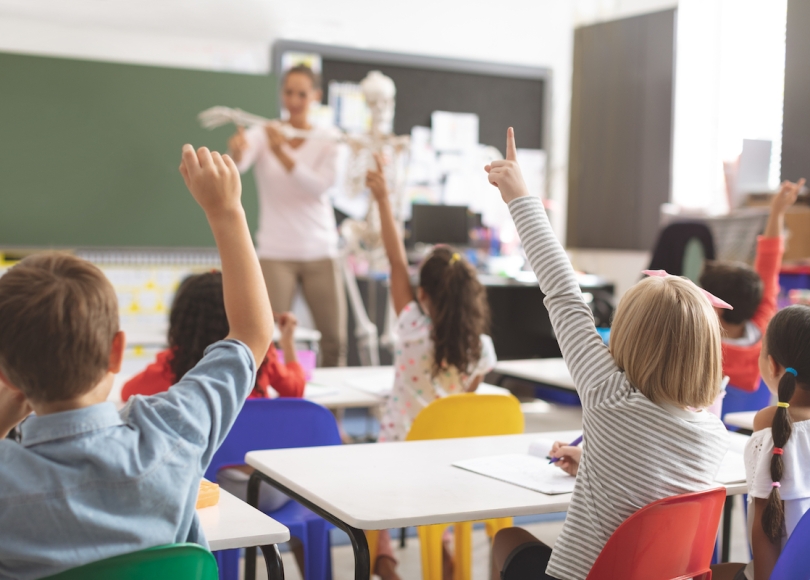 Classroom with children raising their hands